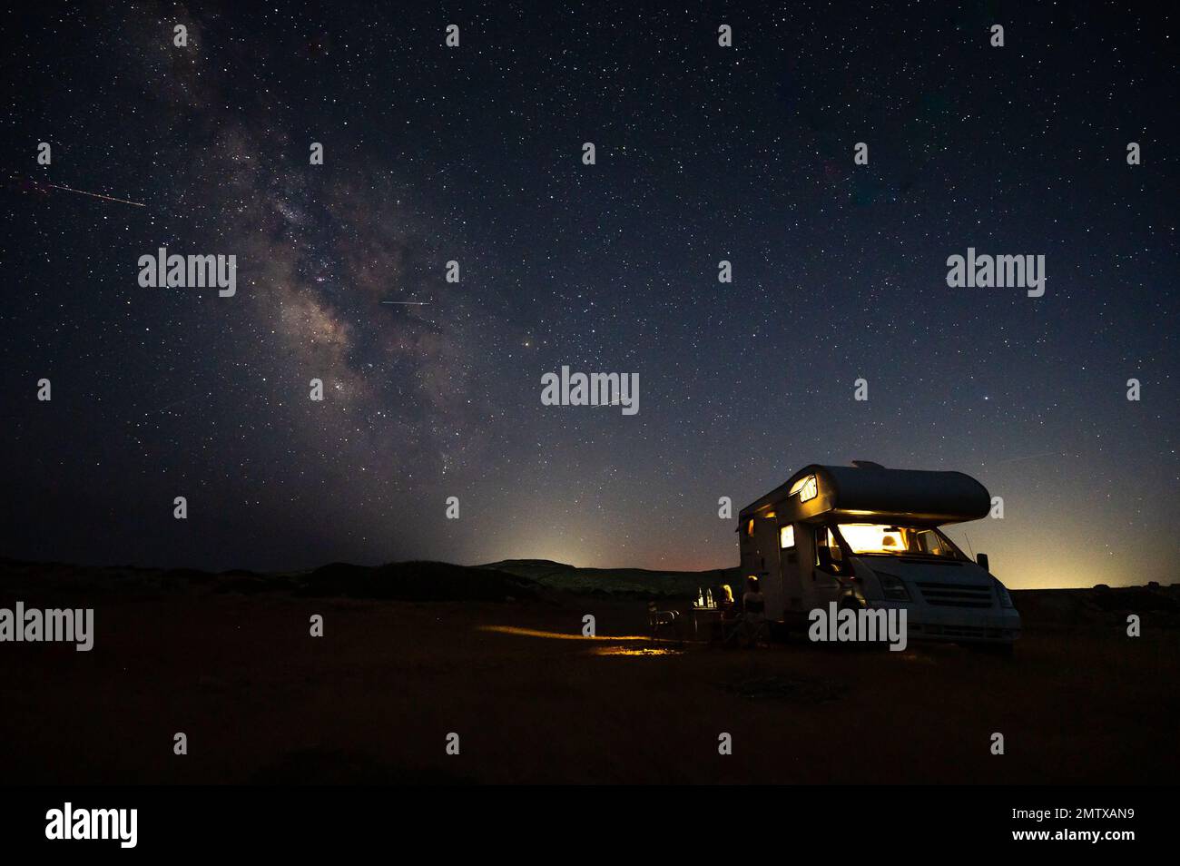 Wohnmobil RV geparkt unter Sternen auf einem Pier am Meer, Kreta, Griechenland. Reisende mit Wohnmobil ruhen sich über Nacht unter milchiger Straße auf einer aktiven Familie aus Stockfoto