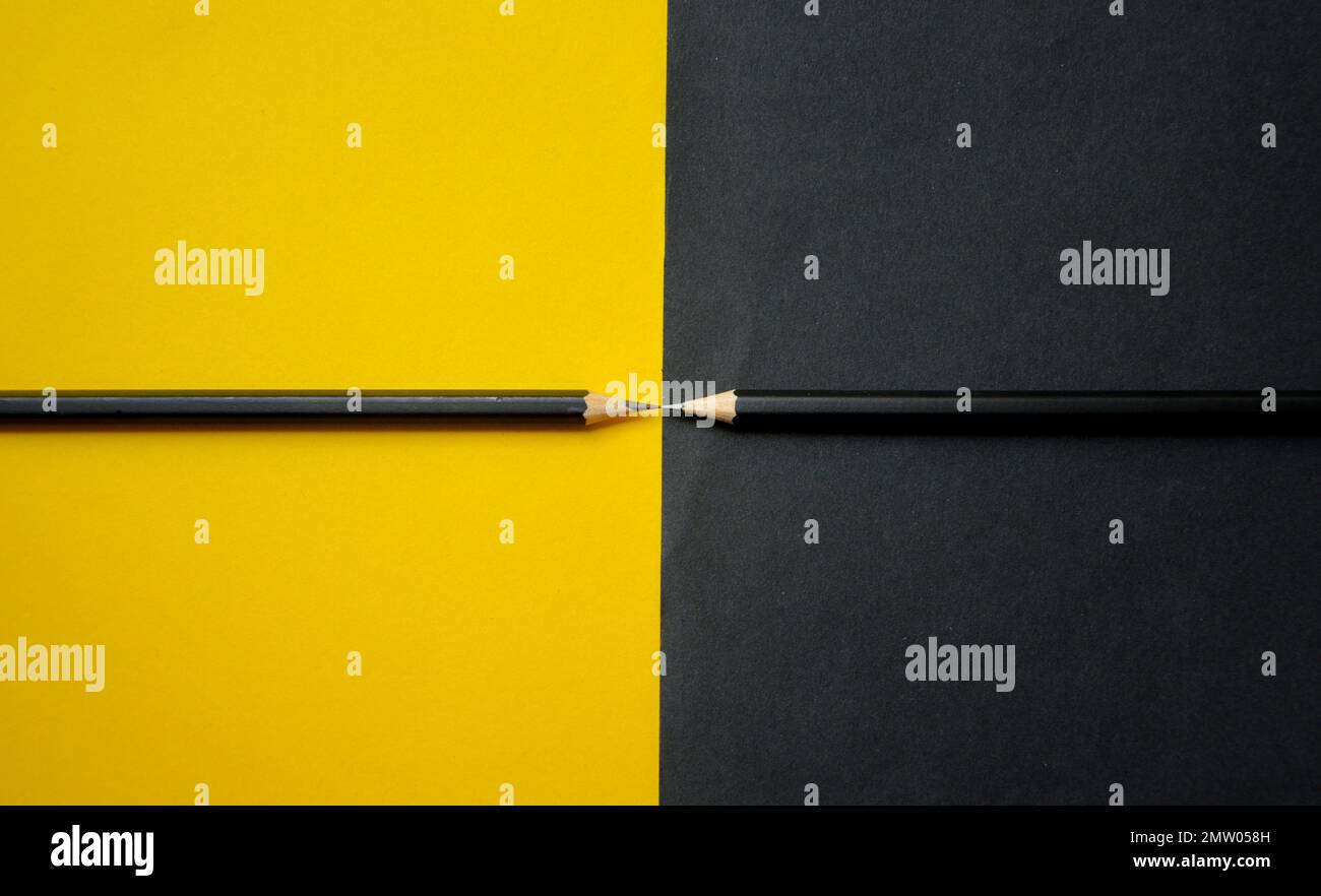 Zwei Bleistifte auf schwarz-gelbem Papier, abstrakt Stockfoto