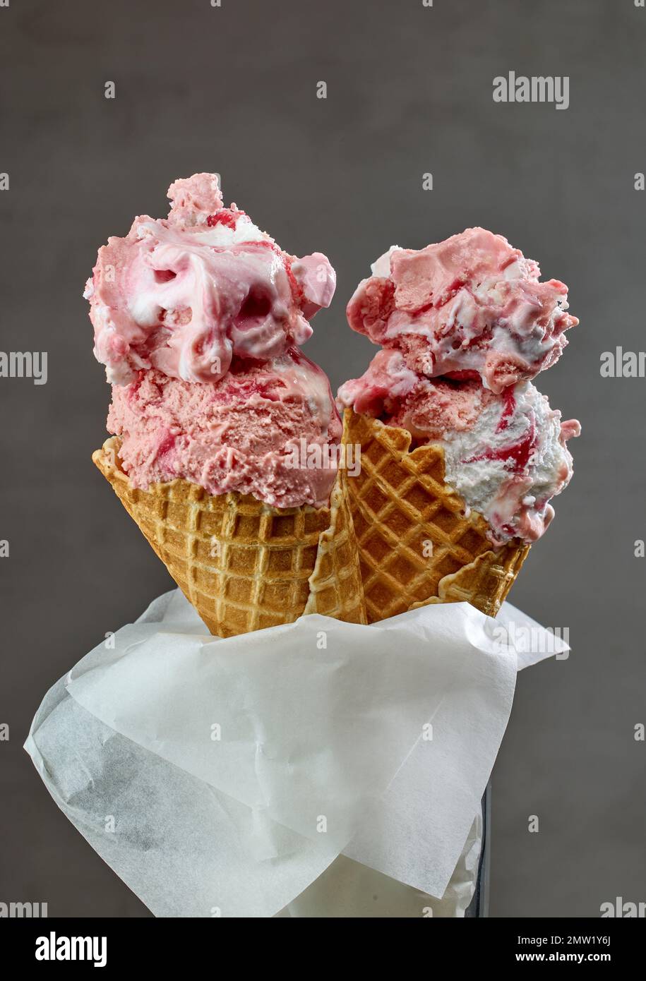 Erdbeereis in Waffelzapfen auf grauem Hintergrund Stockfoto