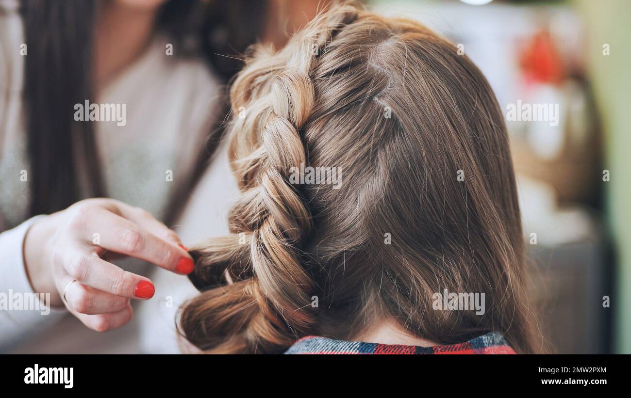 Die Make-up-Künstlerin macht einen Zopf für das Model. Stockfoto