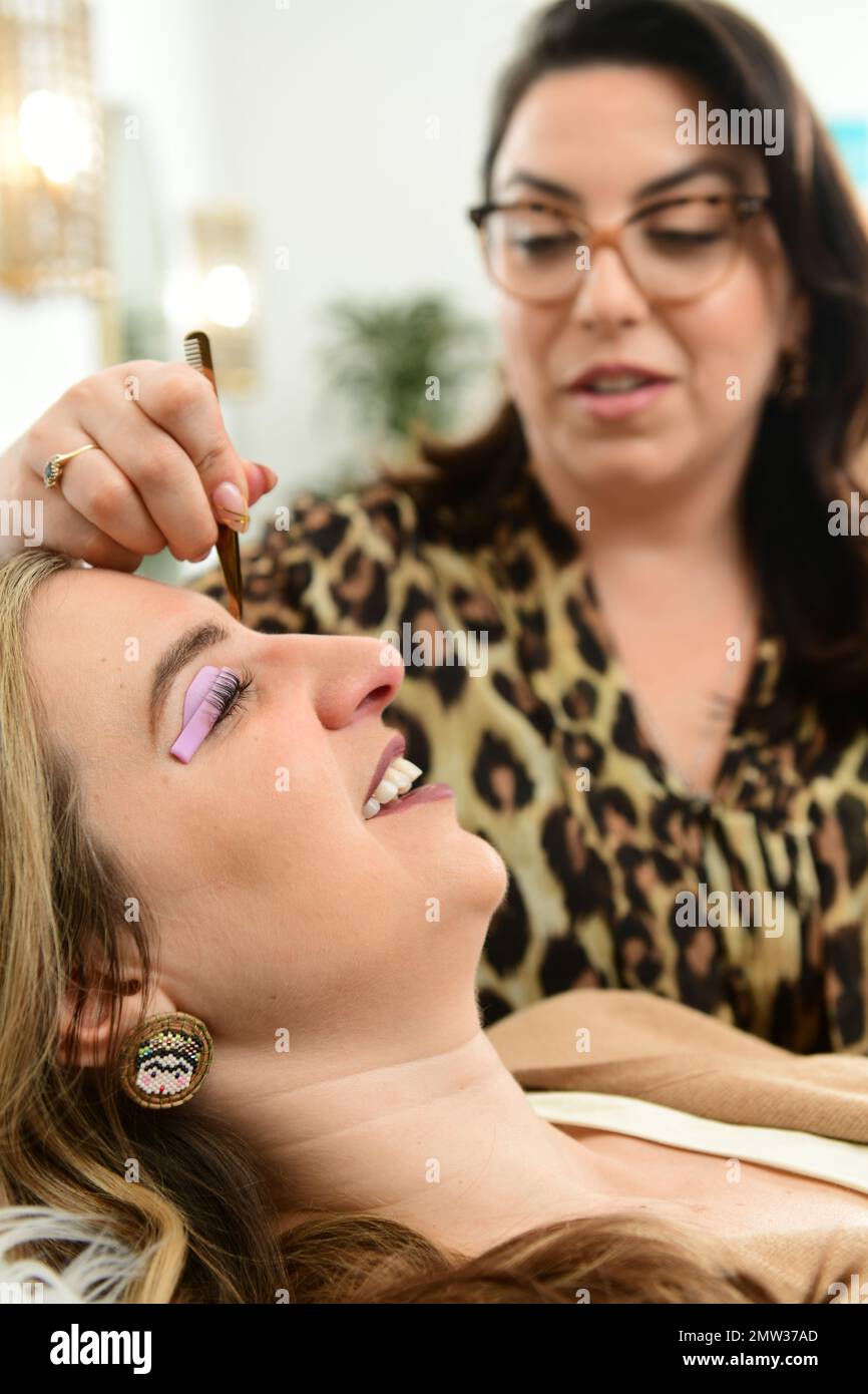 Ein Kosmetiker bearbeitet die Augenbrauen und Wimpern eines Kunden in einem Wellnessbereich Stockfoto