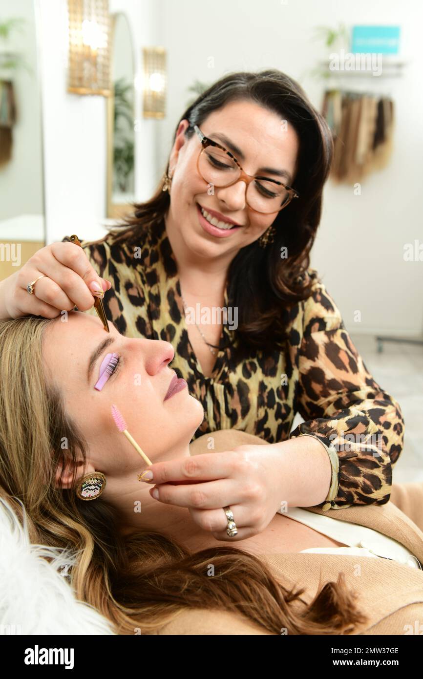 Ein Kosmetiker bearbeitet die Augenbrauen und Wimpern eines Kunden in einem Wellnessbereich Stockfoto