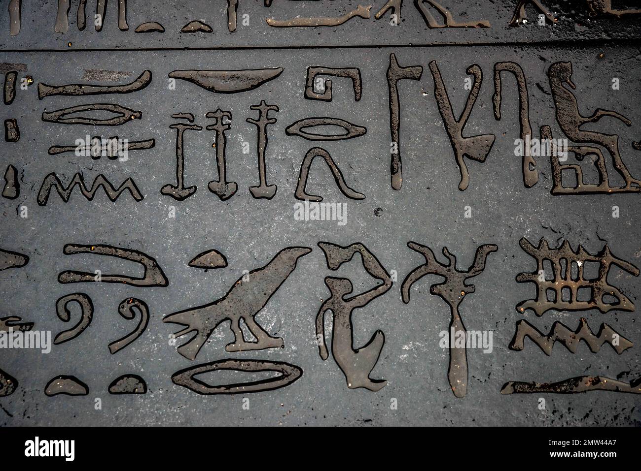 Ein riesiges Exemplar des Rosetta-Steins von Joseph Kosuth in Figeac, Frankreich, am Fuße des Geburtsorts von Jean-Francois Champollion in Figeac in der Lot-Abteilung, ist der Ort des Schreibens. Auf dem Boden liegt eine riesige Scheibe schwarzen Granits, die den Erlass zu Ehren des pharaos Ptolemäus gegen Epiphanes im Jahre 196 v. Chr. auf dem Place des ecritures in Figeac, Frankreich, am 31. Januar 2023 reproduziert. Der Rosetta-Stein ist eine Stele aus Granodiorit, die in drei Versionen eines Dekrets eingeprägt ist, das 196 v. Chr. in Memphis, Ägypten, während der ptolemäischen Dynastie im Namen von König Ptolemäus V Epiphanes erlassen wurde. Der obere und der mi Stockfoto