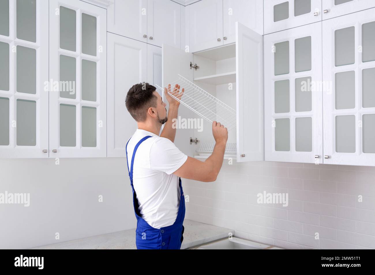 Arbeiter, der Schränke mit Regalen in der Küche installiert Stockfoto