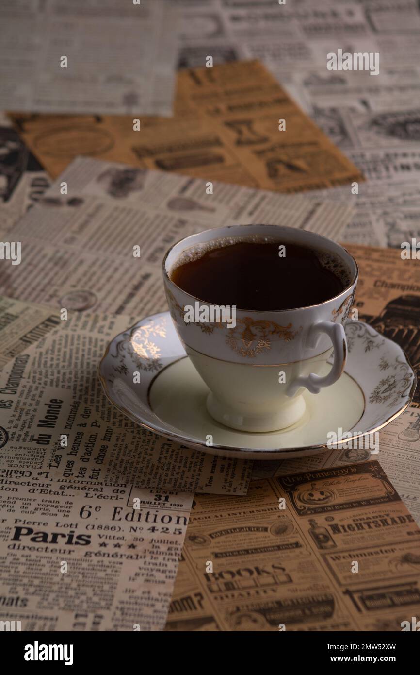 Foto einer Kaffeetasse im Retro-Stil mit alten Zeitschriftenzeitungen im Hintergrund Stockfoto