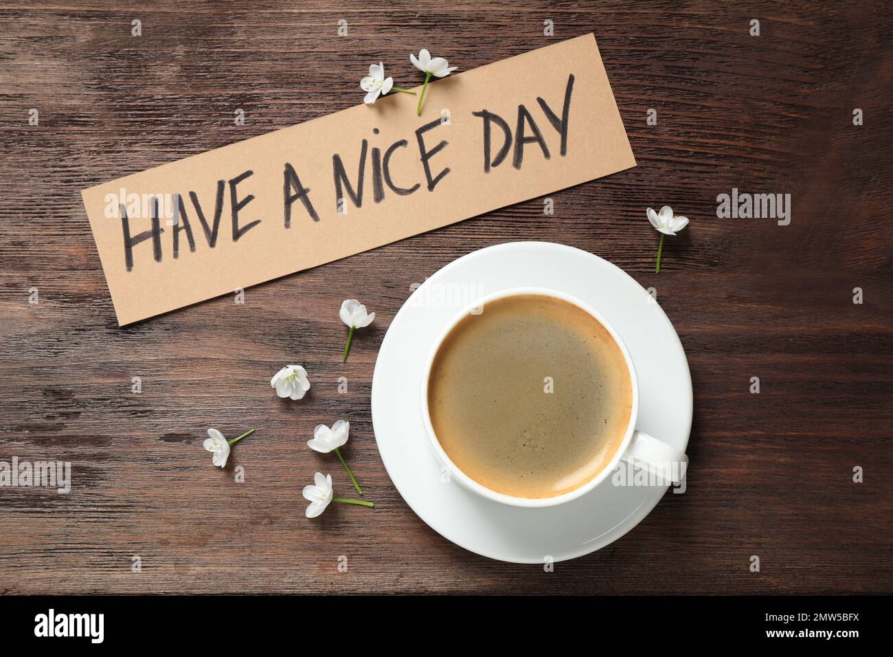 Köstlicher Morgenkaffee, Blumen und Karte mit EINEM SCHÖNEN TAGESWUNSCH auf einem Holztisch, flach liegend Stockfoto