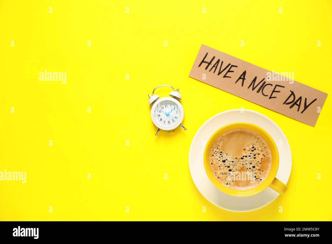 Köstlicher Morgenkaffee, Wecker und Karte mit HAVE A NICE DAY wish auf gelbem Hintergrund, flach liegend. Platz für Text Stockfoto