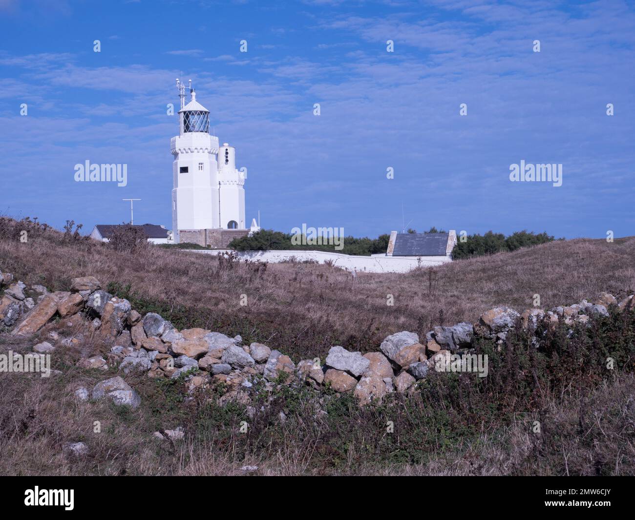 St. Catherine St. Catherine's Lighthouse, Isle of Wight eine geschwungene, geschwungene, trockene Steinwand im Vordergrund unter blauem, wolkigen Himmel an der Küste Stockfoto
