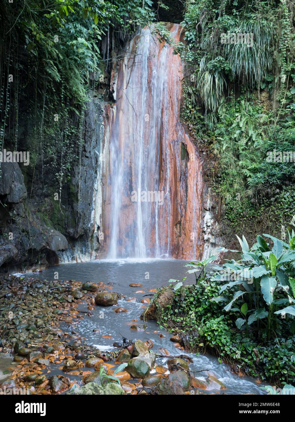 Ein Blick von der Vorderseite auf den Diamond Botanical Gardens Wasserfall mit rot-orangefarbenem Felsenpool und Fluss, der auf die langsame Verschlusszeit der Kamera zugeht Stockfoto