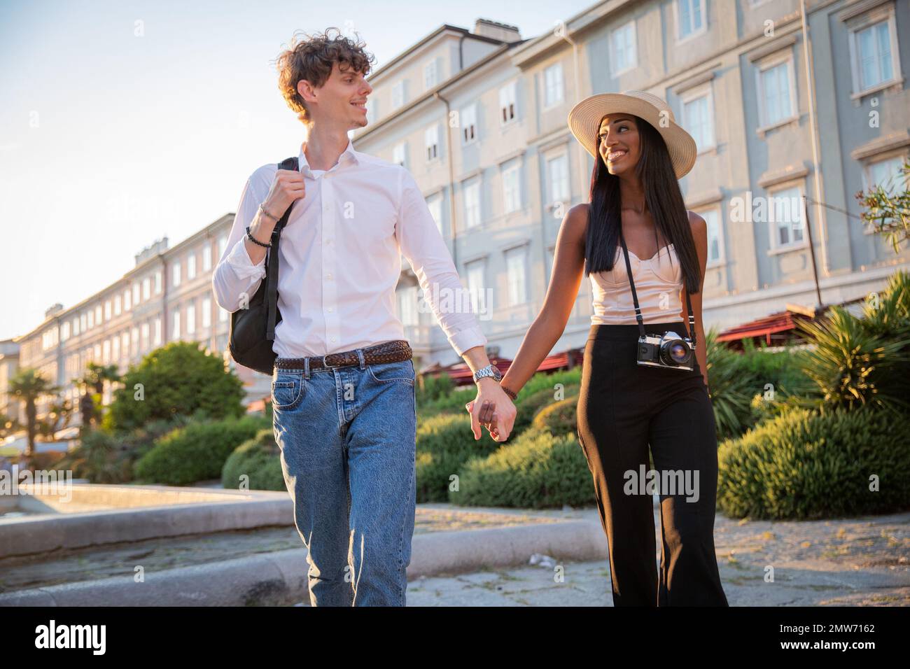 Ein multiethnisches Paar im Urlaub, das Händchen hält und im Stadtzentrum spaziert Stockfoto