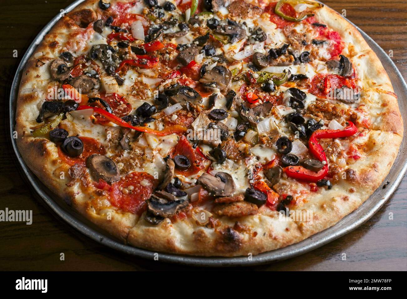 Gourmet-Pizza mit Peperoni, Würstchen, weißen Zwiebeln, Pilzen, roten Paprika, Und schwarze Oliven Stockfoto