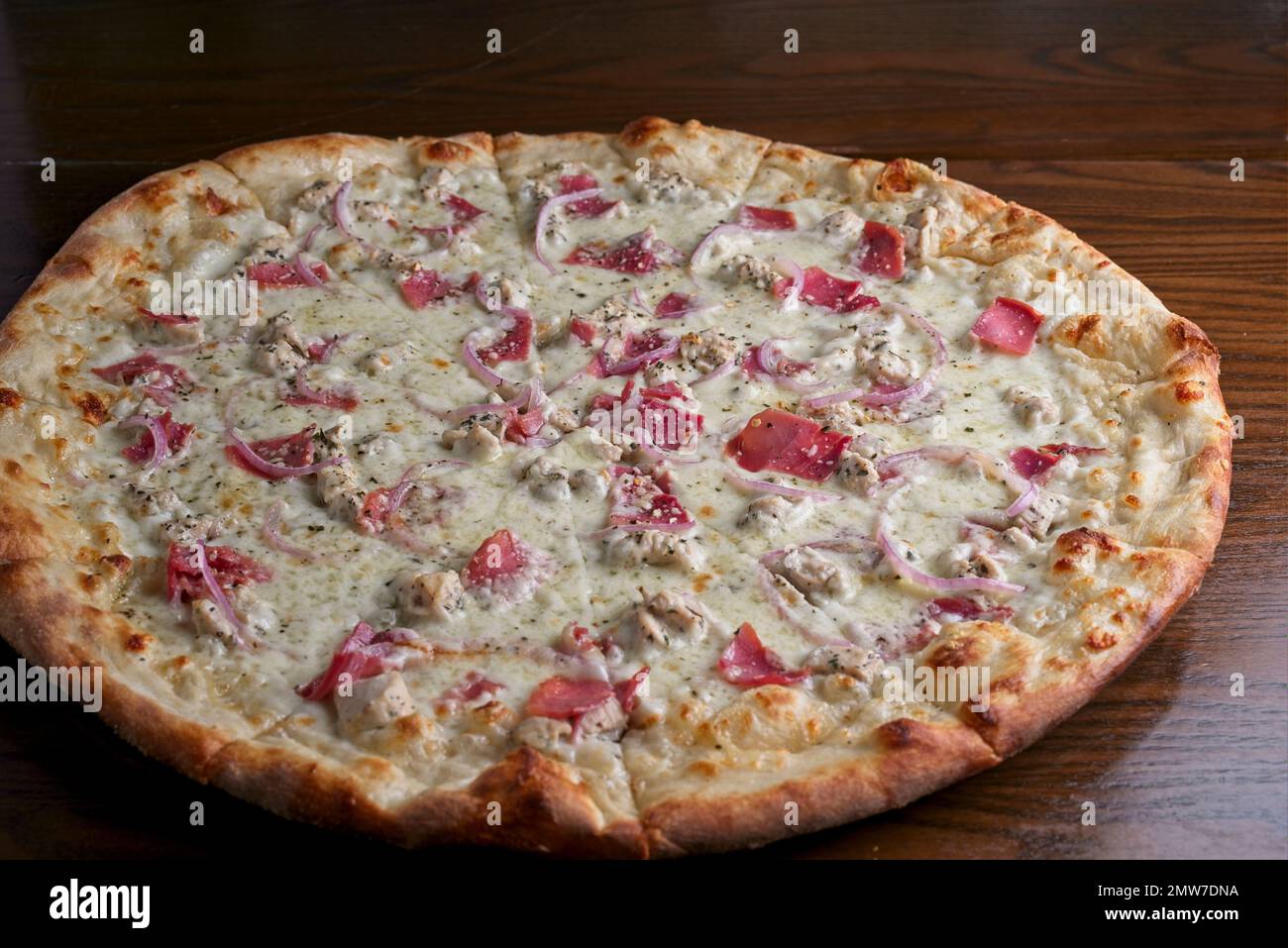 Weiße Gourmet-Pizza-Pastete mit Huhn, Prosciutto, roten Zwiebeln und dünner Kruste Stockfoto