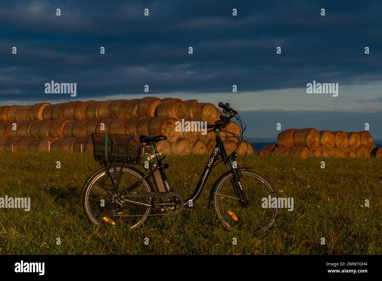 Heubälle und Elektrofahrrad auf dem Feld bei Ceske Budejovice Stadt in Sonnenaufgang Zeit in Farbe Herbst Stockfoto