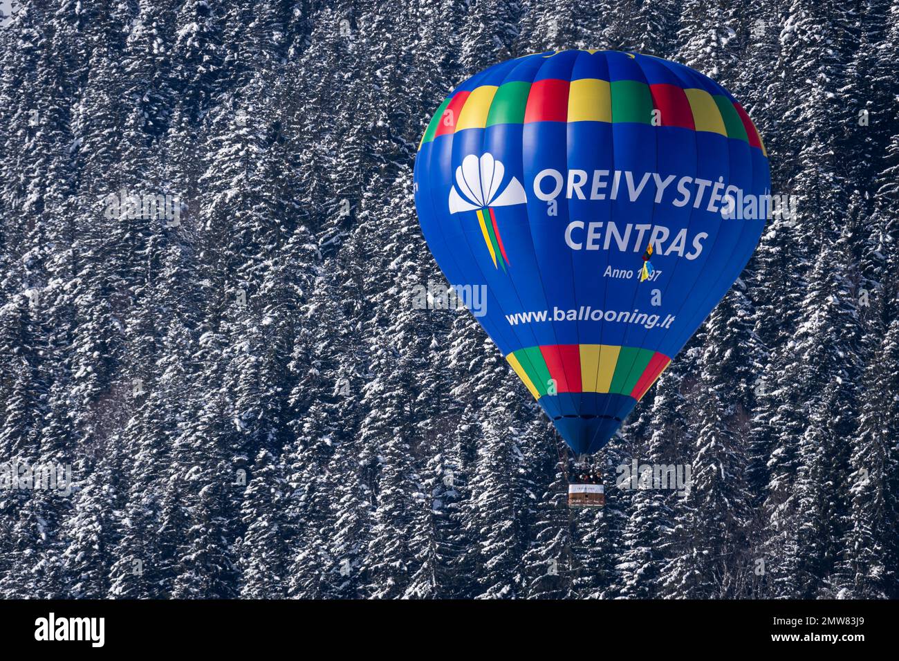 Chateau-d'Oex, Vaud, Schweiz - 23. Januar 2023: Heißluftballon im Flug. Oreivystes centras Heißluftballonfahrt gegen den Wald in Switzerla Stockfoto