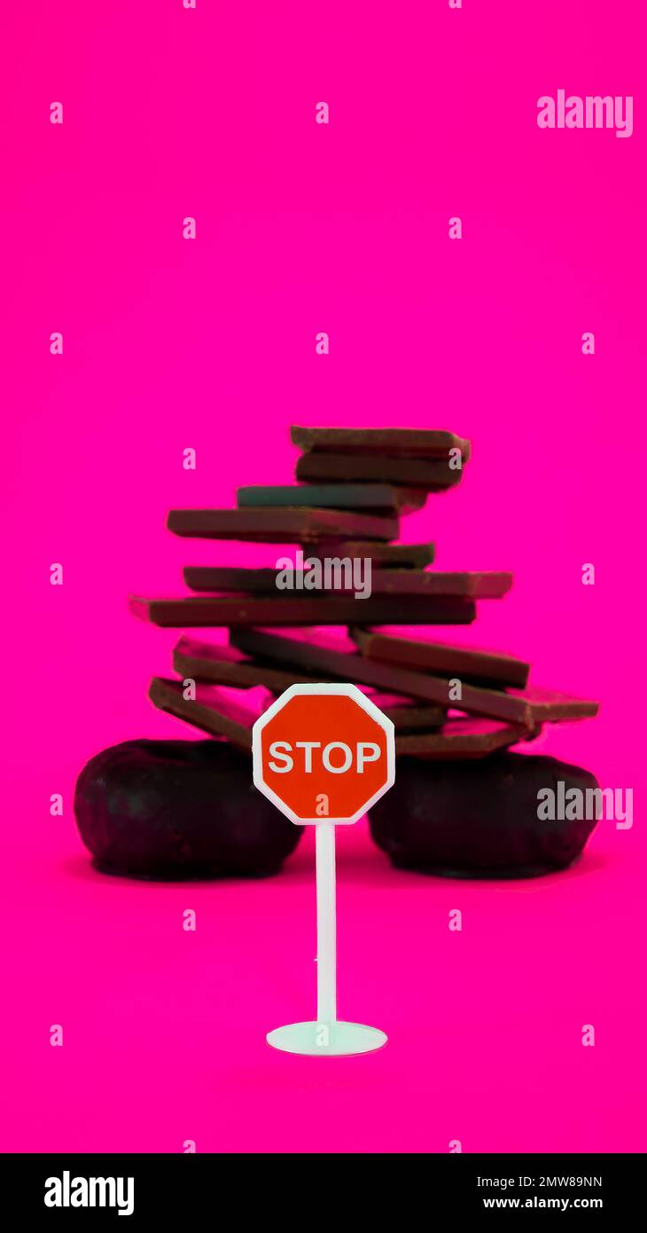 Schokolade und Donuts isoliert auf pinkfarbenem Hintergrund mit Stoppschild Stockfoto