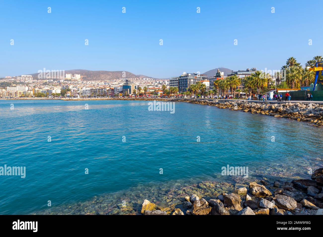 Touristen und Einheimische spazieren entlang der Uferpromenade entlang der Mittelmeerküste im Hafen von Kusadasi. Stockfoto