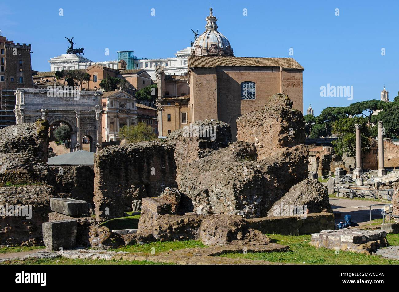 Ruine mit Fundamentmauern und Fundament des Tempels von Gaius Julius Cäsar, Divus Iulius, hinter dem historischen Gebäude des Senats von Stockfoto