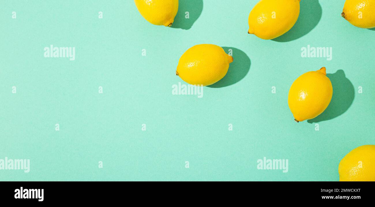 Frische gelbe ganze Zitronen auf minimalblauem Hintergrund auf hellem Sonnenlicht mit harten Schatten Muster Sommer Hintergrund flach von oben, Zitrusfrüchte Lebensmittel Stockfoto
