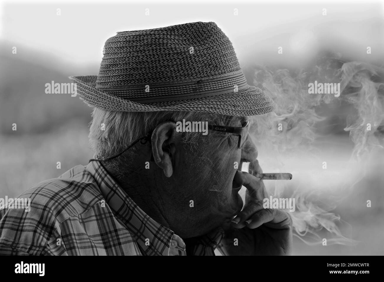 Alter Mann mit Strohhut raucht Zigarette und raucht, Spanien Stockfoto