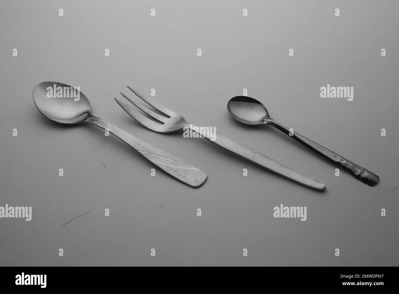 Silberner Löffel, Gabeln und Messerbesteck isoliert auf dem leeren grauen Tischhintergrund Stockfoto