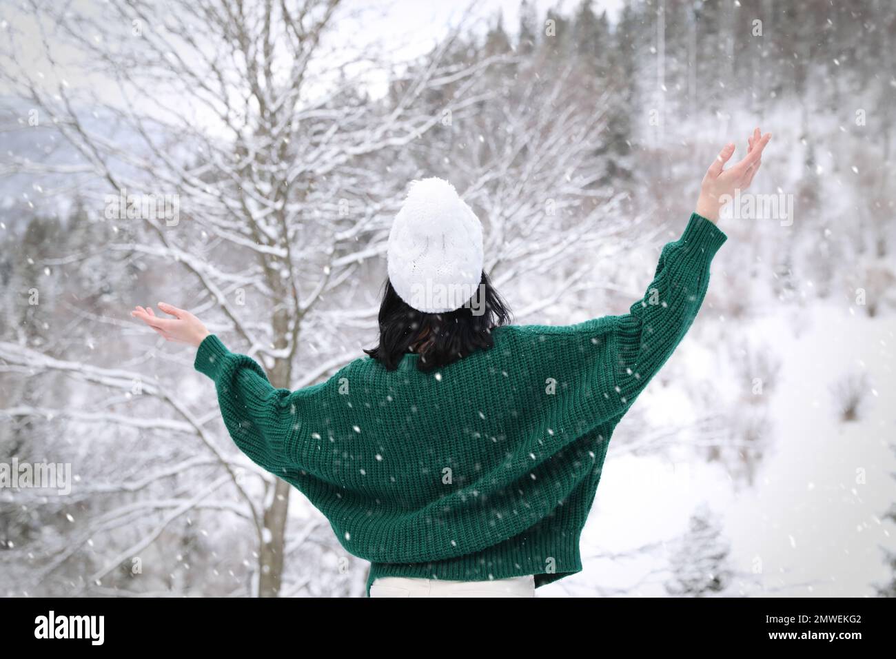 Eine Frau, die im Winterwald einen warmen Pullover trägt Stockfoto