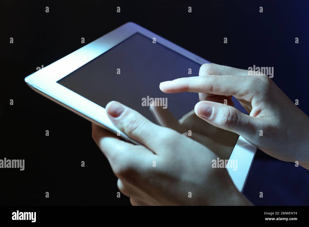Frau, die ein Tablet auf dunklem Hintergrund benutzt, Nahaufnahme Stockfoto