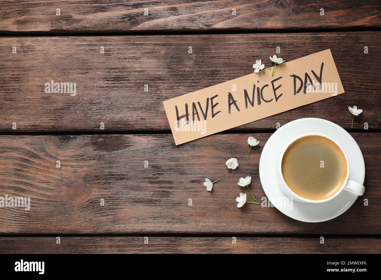 Köstlicher Morgenkaffee, Blumen und Karte mit EINEM SCHÖNEN TAGESWUNSCH auf einem Holztisch, flach liegend. Platz für Text Stockfoto