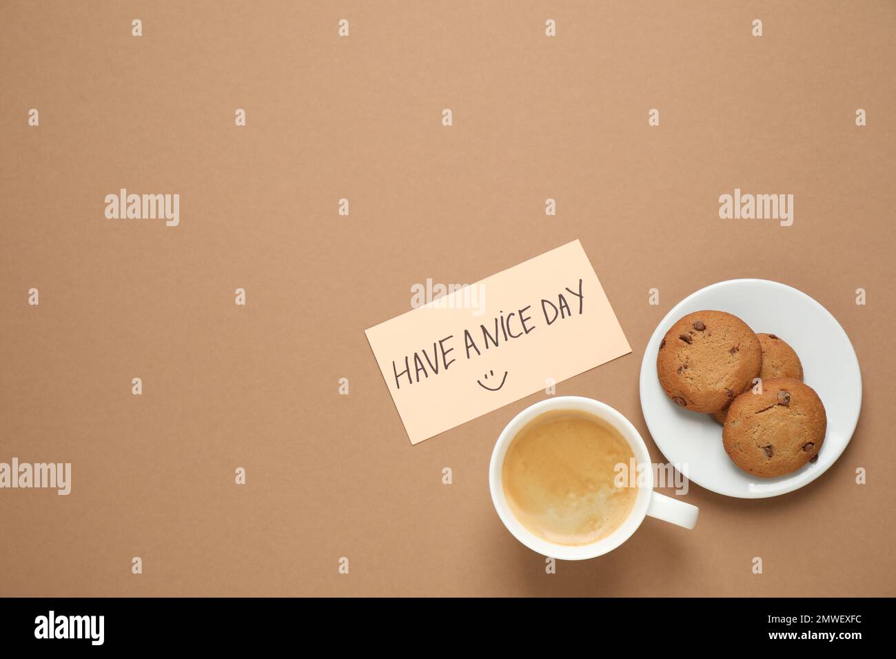 Köstlicher Morgenkaffee, Kekse und Karte mit EINEM SCHÖNEN TAGESWUNSCH auf braunem Hintergrund, flach liegend. Platz für Text Stockfoto