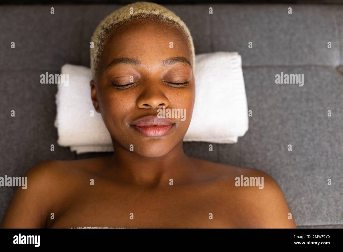 Glückliche afroamerikanische Frau, die mit geschlossenen Augen auf einem Handtuch lag Stockfoto