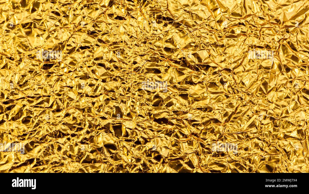 Leuchtend gelbe Textur aus zerknitterter und geknitterter Goldfolie oder Blatt als Hintergrund. Stockfoto