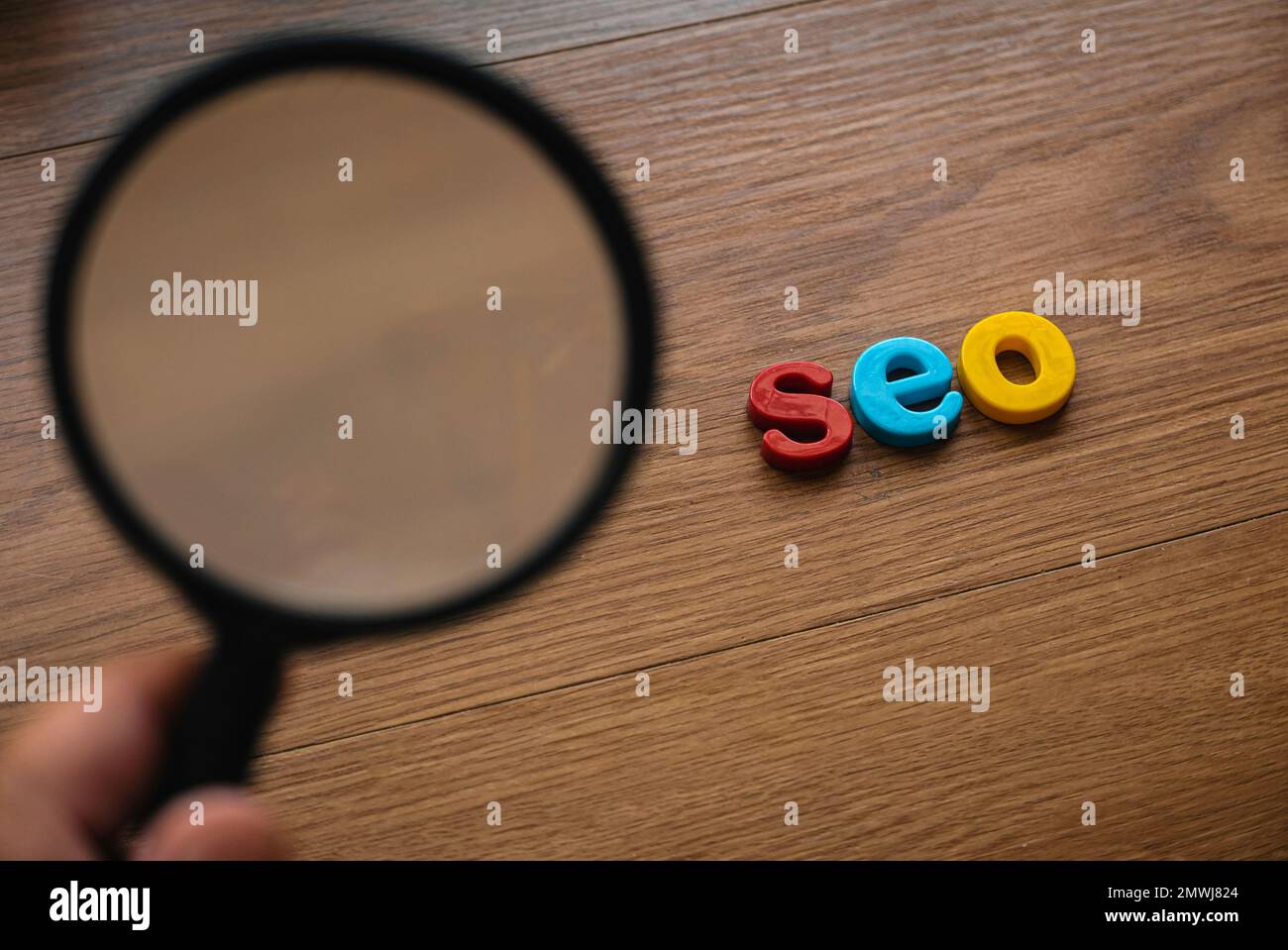 Konzept der Suchmaschinenoptimierung. Lupe und seo-Alphabet auf Holzhintergrund. Stockfoto