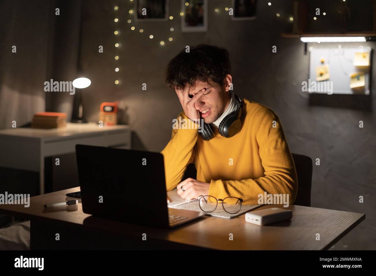 Müde, erschöpfter araber, Student im Studentenwohnheim oder Freiberufler, sitzt an seinem Schreibtisch, müde vom Lernen in einem Laptop, überarbeitet, hat Kopfschmerzen Stockfoto