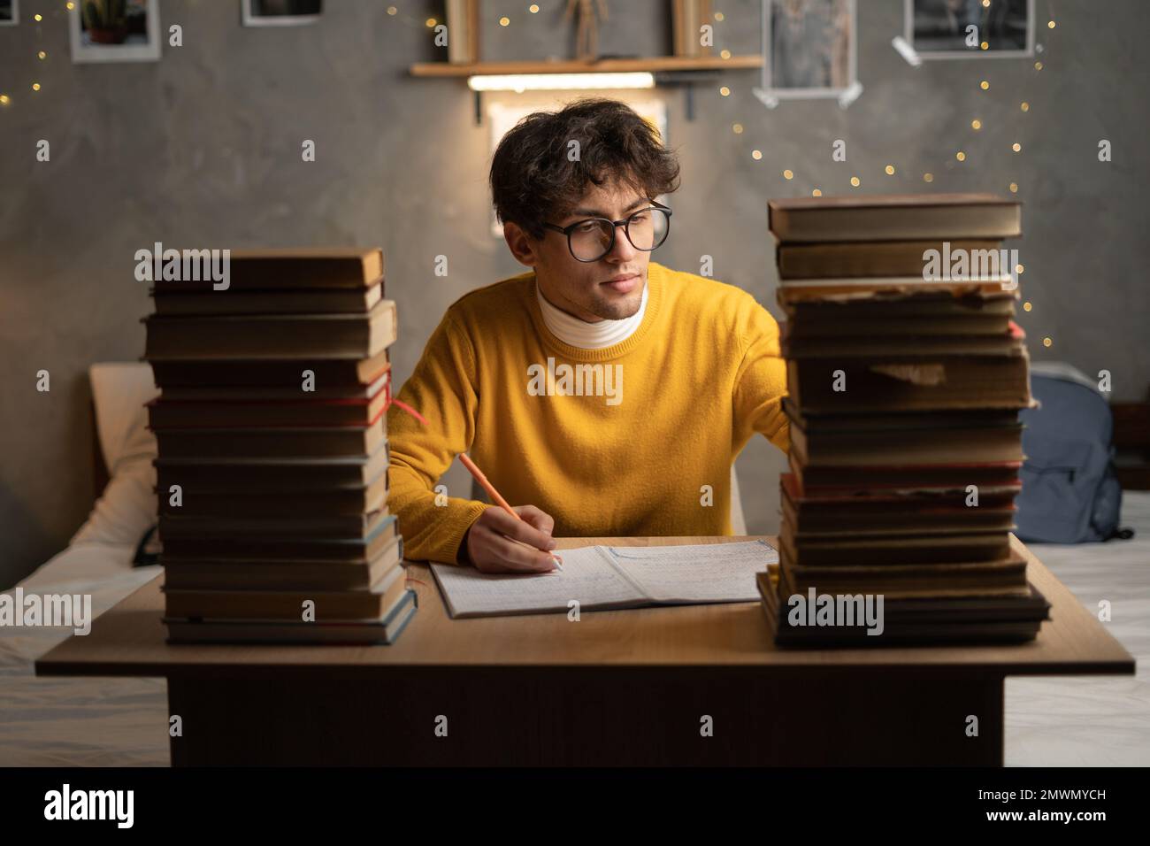 Frustrierter Student, der am späten Abend oder Abend vor der Prüfung studiert, Schüler mit einem Haufen Bücher, der hart für die Prüfung in der Highschool lernt. Kopie SPA Stockfoto