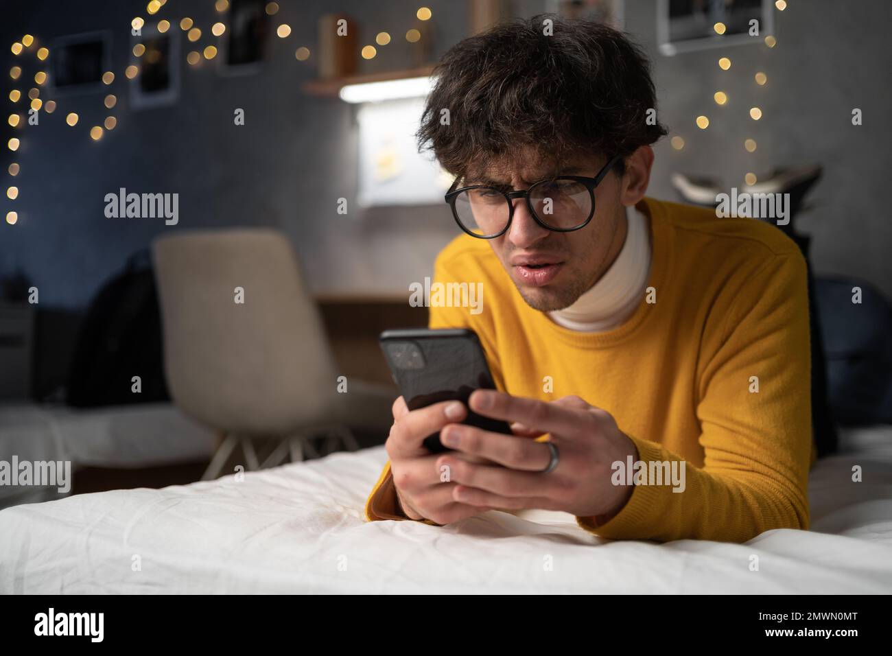 Verärgert verwirrter junger Mann mit Handy, Problem mit Handy oder verpasstem Anruf, frustrierter wütender Student, der schlechte Nachrichten in Nachricht l liest Stockfoto