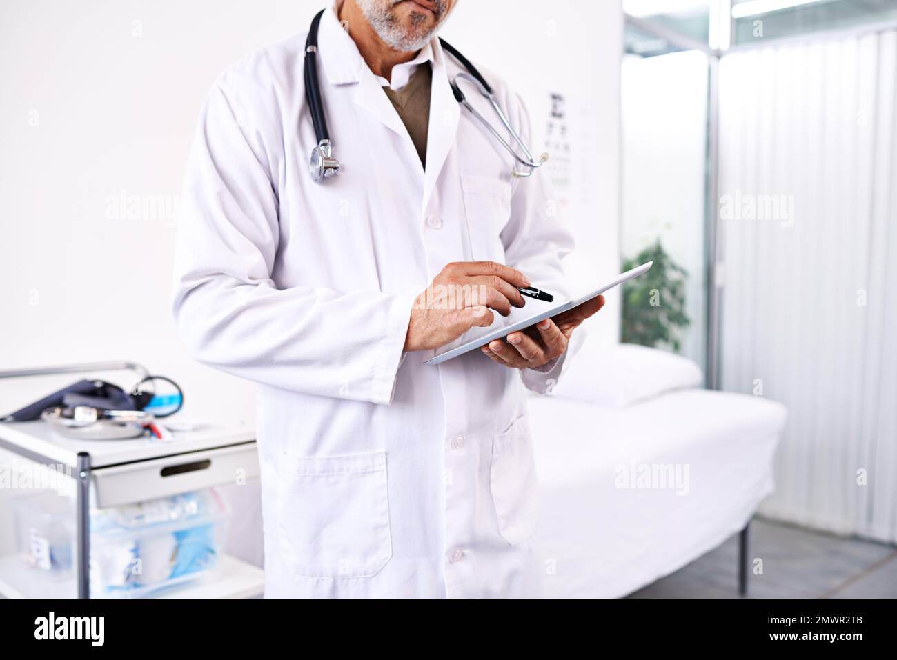 Die Testergebnisse durchgehen. Ein männlicher Arzt, der ein digitales Tablet in einem Krankenhaus benutzt. Stockfoto