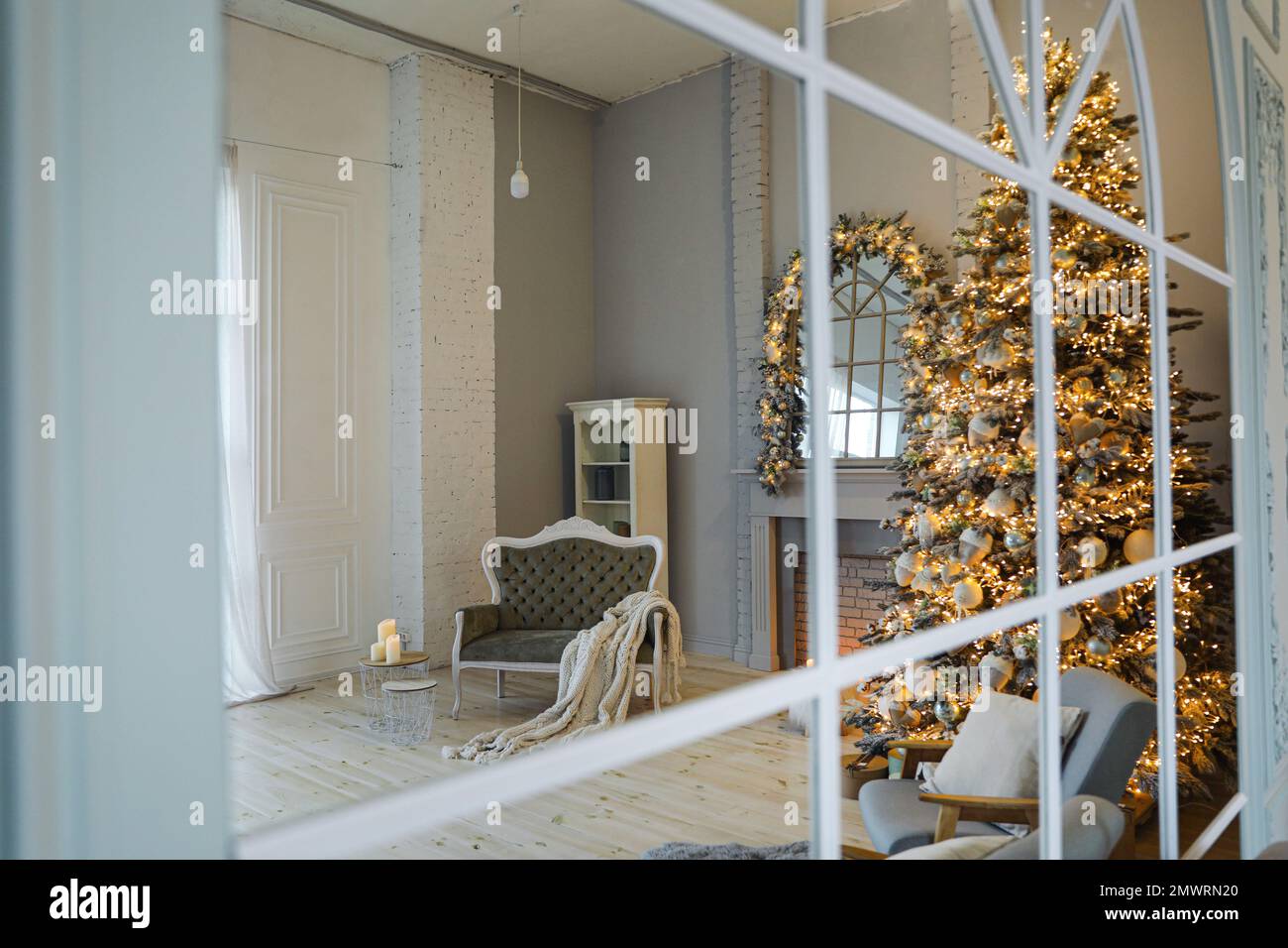 Festliche Innenausstattung mit stilvollen Möbeln und wunderschönem Weihnachtsbaum, Blick durch das Fenster Stockfoto