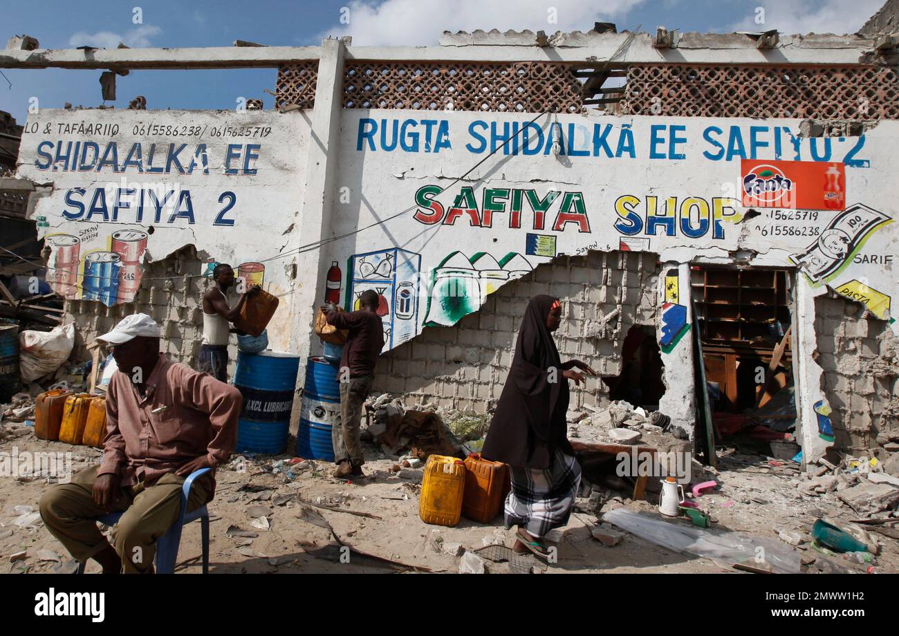 A Somali man sits next to the remains of his partially destroyed fuel shop near the scene of a suicide car bomb attack on a police station adjacent to the seaport in the capital Mogadishu, Somalia Sunday, Dec. 11, 2016. The suicide car bomber killed a number of people, and Islamic extremist rebels al-Shabab claimed responsibility for the attack. (AP Photo/Farah Abdi Warsameh) Stockfoto