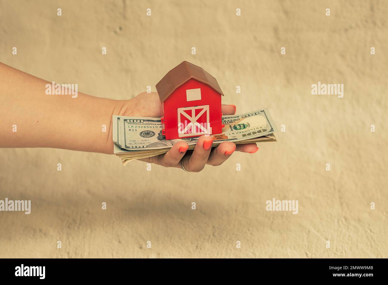 Rotes Haus mit einem Stapel von Dollarscheinen. Das Konzept des Kaufs eines Hauses. Stockfoto