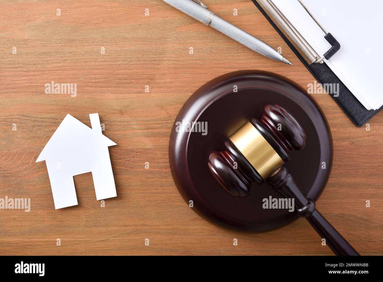 Wohnversuchskonzept mit Hammer und Ausschnitt aus einem Haus auf einem Holztisch. Draufsicht. Stockfoto