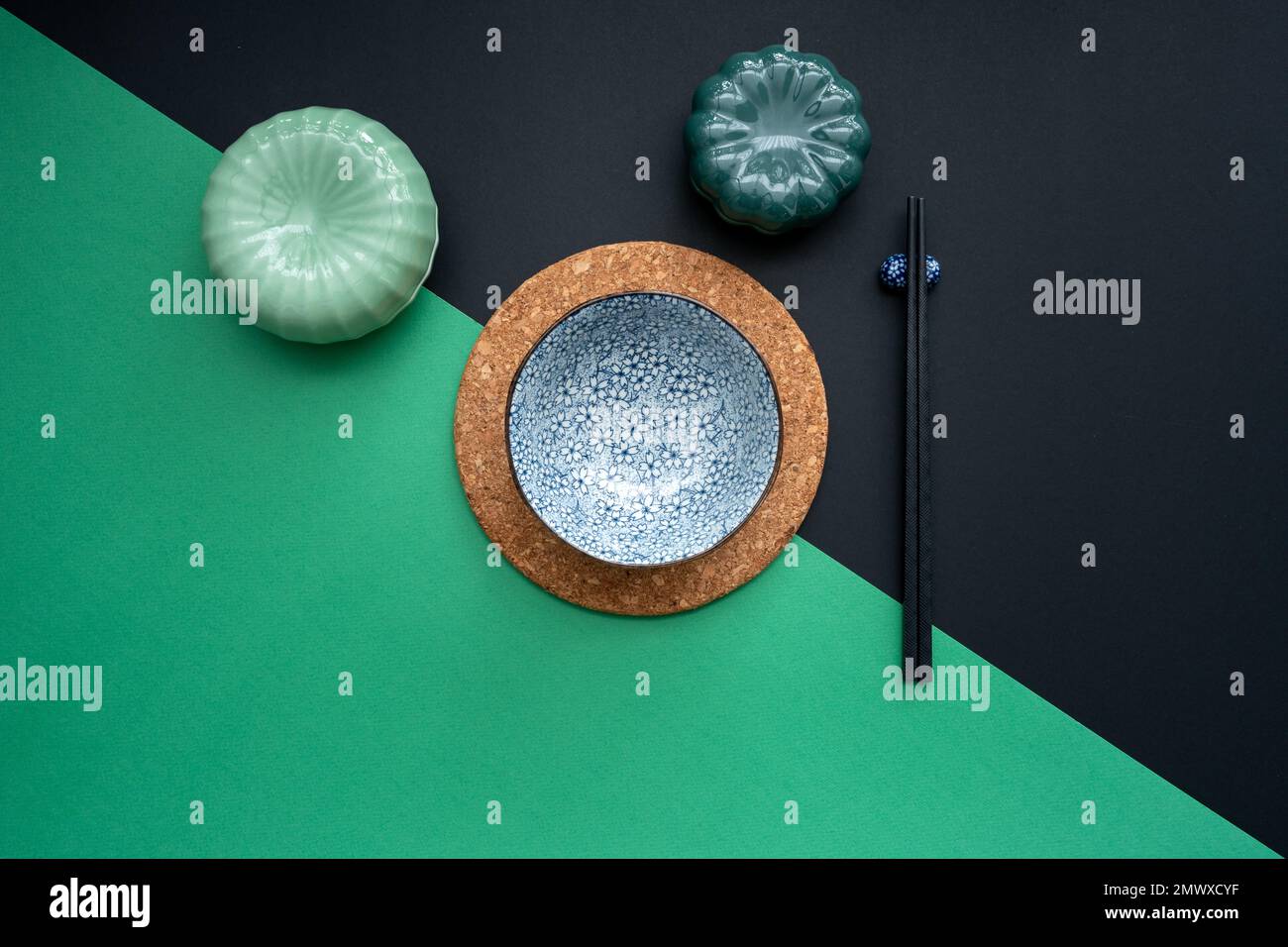 Japanischer oder chinesischer Tisch mit traditioneller Tischdecke und Essgeschirr mit grünem und schwarzem Hintergrund. Essen, Essen, Essen und Trinken Konzept. Stockfoto