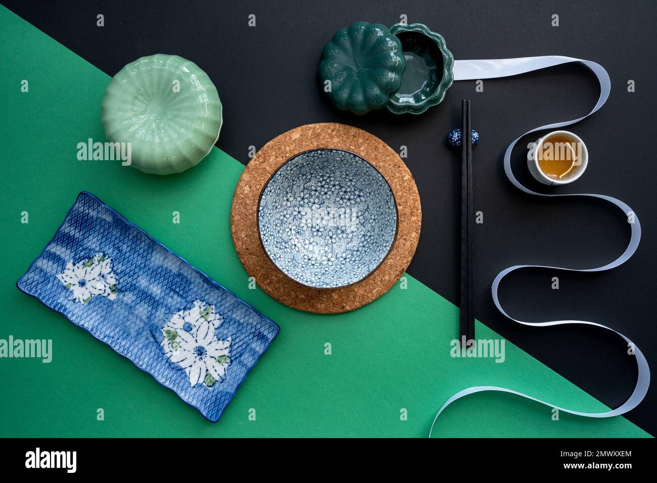 Japanischer oder chinesischer Tisch mit traditioneller Tischdecke und Essgeschirr mit grünem und schwarzem Hintergrund. Essen, Essen, Essen und Trinken Konzept. Stockfoto