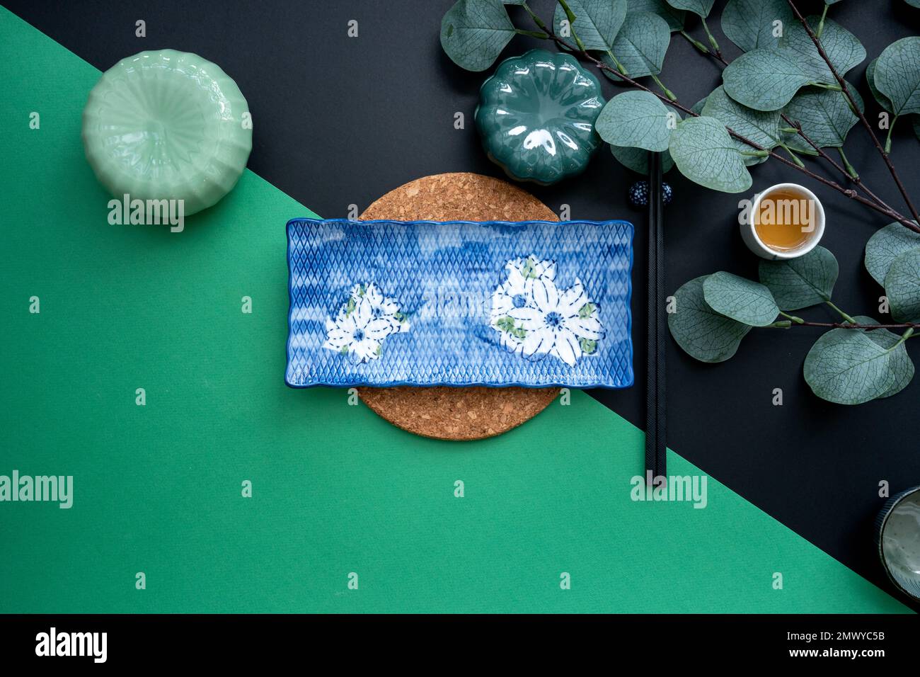Japanischer oder chinesischer Tisch mit traditioneller Tischdecke und Essgeschirr mit grünem und schwarzem Hintergrund. Essen, Essen, Essen und Trinken Konzept. Stockfoto