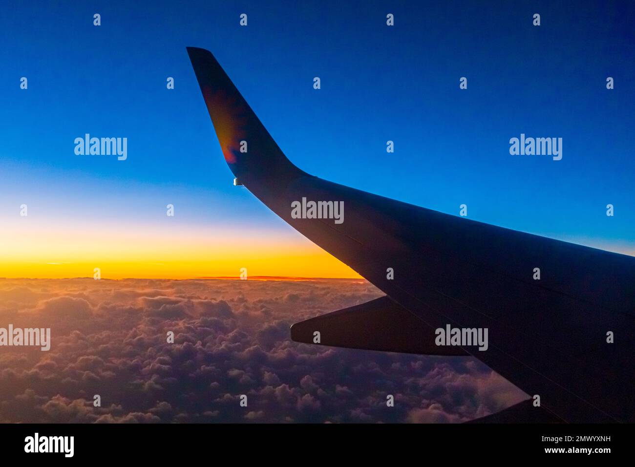 Blick aus dem Passagierfenster eines Boeing 737-Flugzeugs, das über die Wolken bei Sonnenuntergang fliegt Stockfoto
