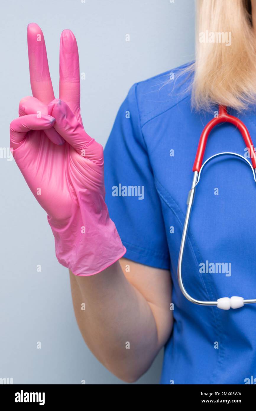 Der Arzt im Krankenhaus zeigt eine Geste, die auf den Sieg hinweist. Der Arzt zeigt eine Geste. Sieg über die Krankheit. Stockfoto