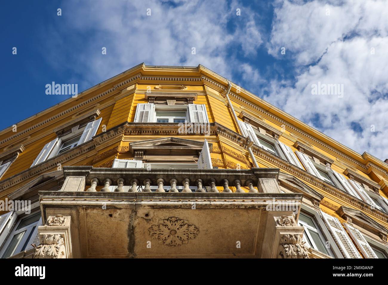 Low-Angle-Architektur in Pula City. Urban Under Blick auf die gelbe Gebäudefassade in Europa mit blauem Himmel und Wolken. Stockfoto