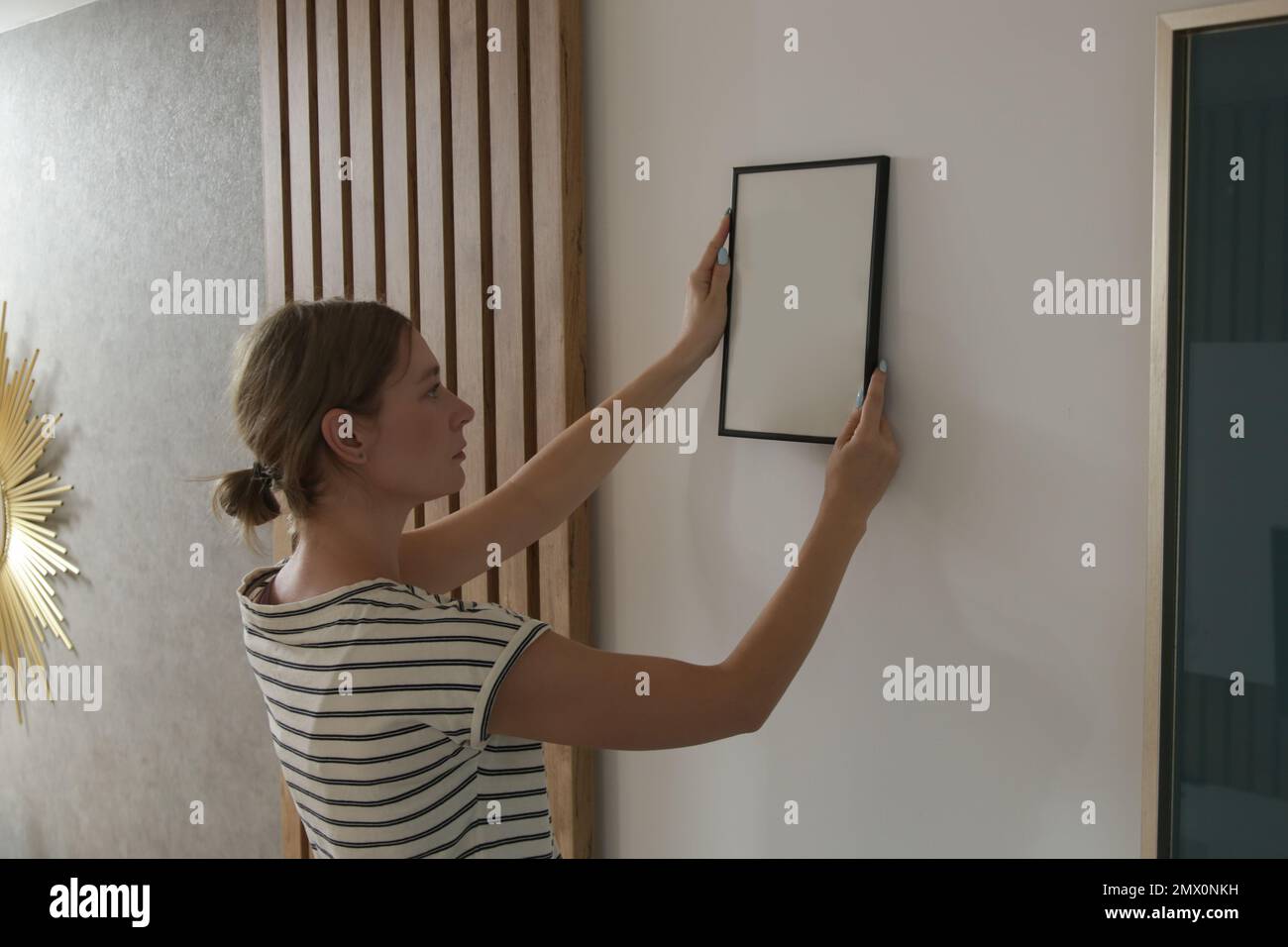 Frau, die Bilderrahmen an der Wand in einem neuen Haus anlegt, heimwerkerkonzept Stockfoto