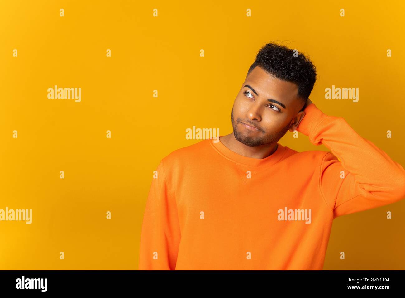 Verwirrter, nachdenklicher junger indischer 20s-Mann, der Zweifel hat, Hand an Kopf legt, keine Ahnung hat, wie man Probleme löst, isoliert auf gelbem Hintergrund Stockfoto