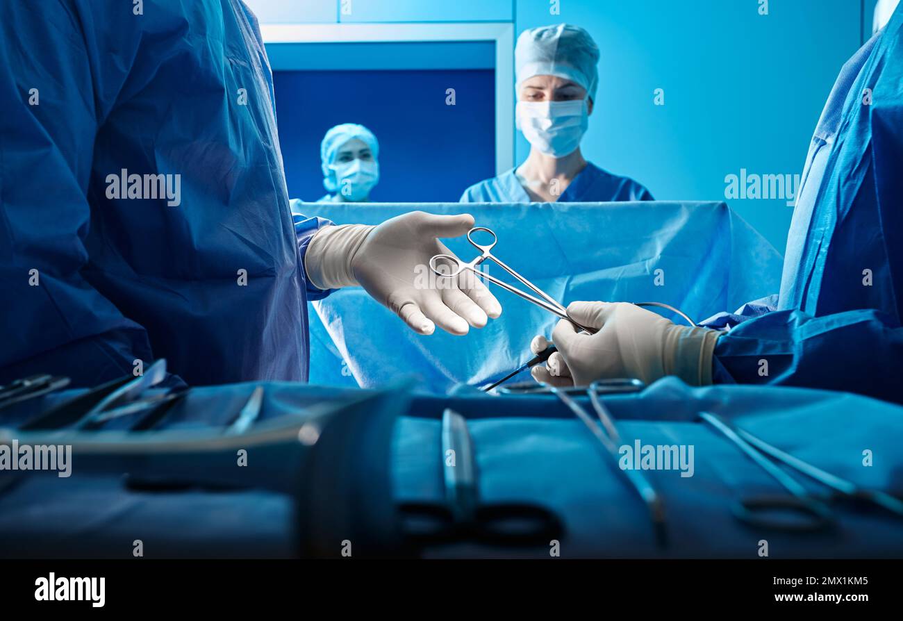 Chirurgen, die chirurgische Eingriffe an Patienten mit chirurgischer Schere im Operationssaal durchführen. Chirurgenteam Stockfoto