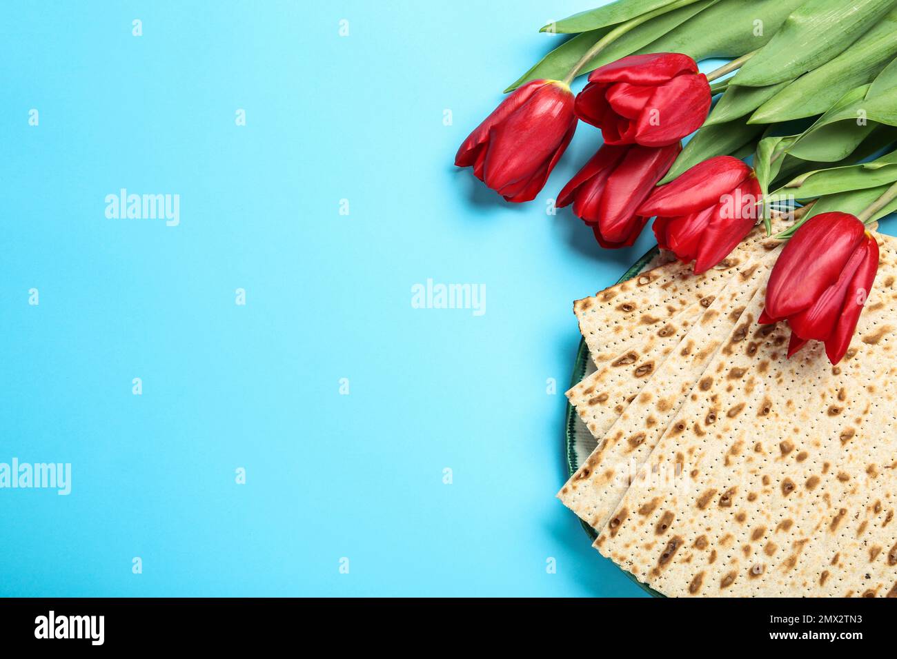Matzen und Blumen auf hellblauem Hintergrund, flach liegend mit Platz für Text. Passover (Pesach) Seder Stockfoto