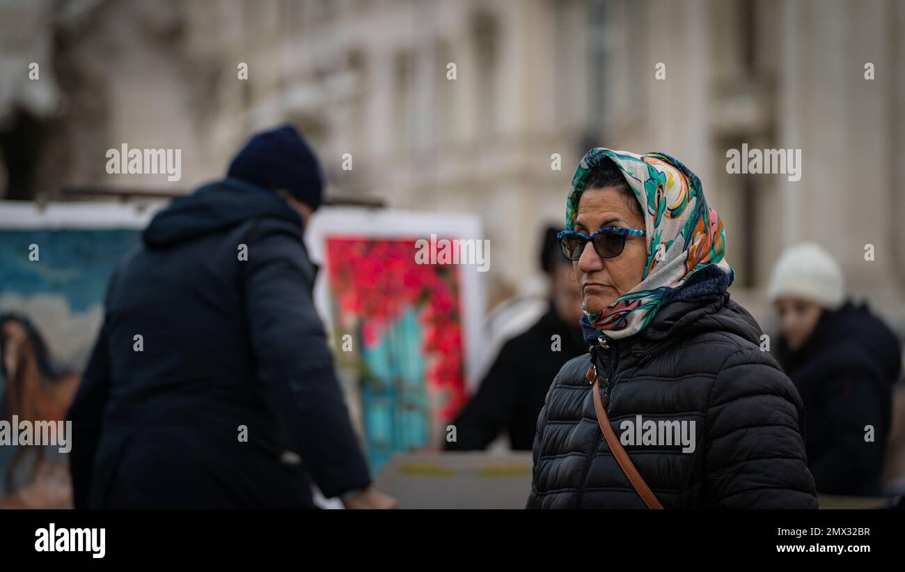Nahaufnahme einer Frau im höheren Alter, die im Winter auf der Piazza Navona, Rom, Italien, mit Schal und Sonnenbrille spaziert. Konzeptleben in der Stadt Stockfoto